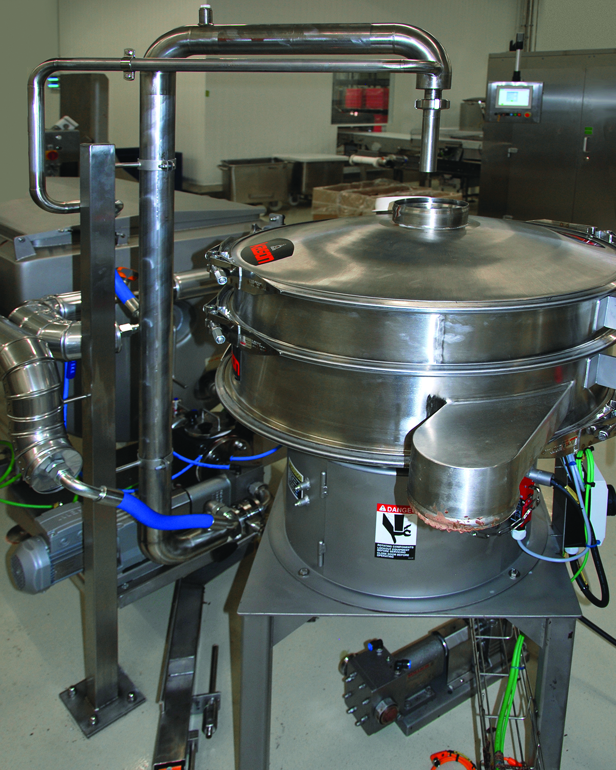 Solids exit through a discharge port at the screen's periphery, while molten chocolate discharges through a lower port and returns to the production process.
